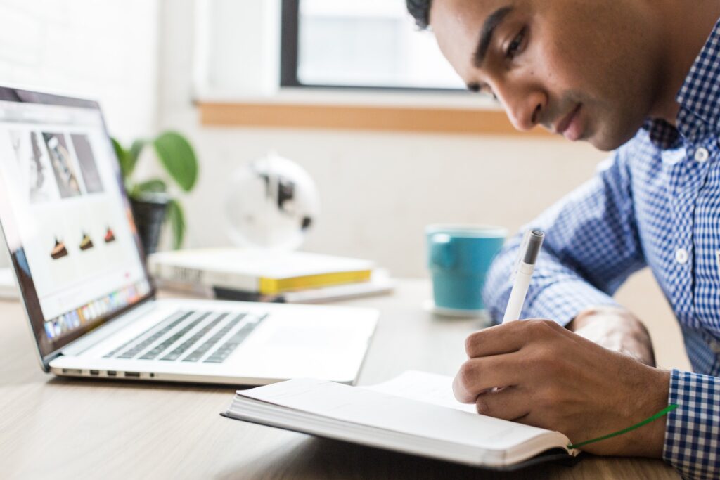 Man taking notes while online tutoring